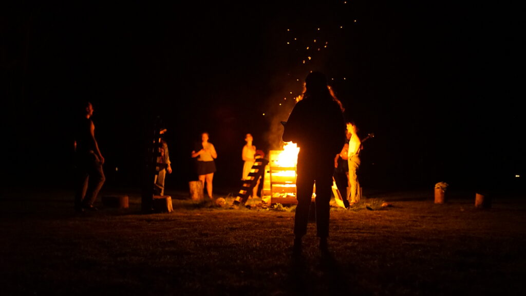 Campers gathered around a nighttime bonfire at Rowe Camp