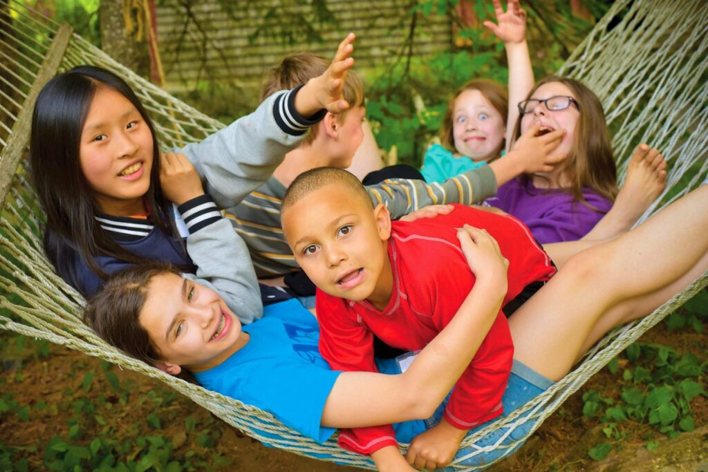 Young campers piled together in a hammock at Rowe Camp