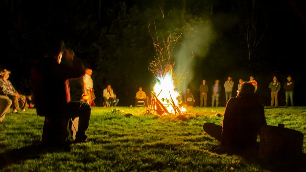 Campers gathered around a campfire at night at Rowe Camp